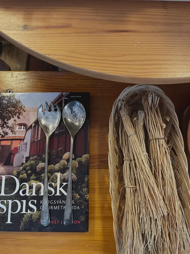 Salladsbestick i silver, kokbok och korg med torkat gräs