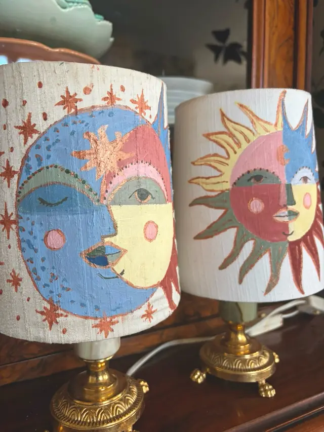 Två handmålade lampskärmar med sol- och månmotiv på mässingsfötter
